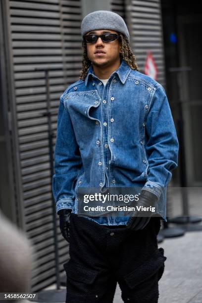 Guest wears grey hat, denim jacket, black gloves outside Sacai during Paris Fashion Week - Menswear Fall-Winter 2023-2024 on January 22, 2023 in...