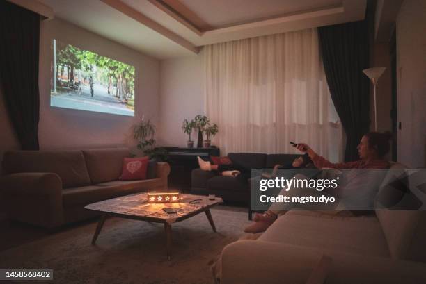 woman watching cinema at home projection in the living room . - projection screen home stock pictures, royalty-free photos & images