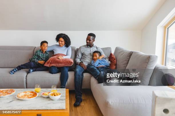 família feliz diversificada desfrutando de tempo juntos em um sofá - family and happiness and diverse - fotografias e filmes do acervo