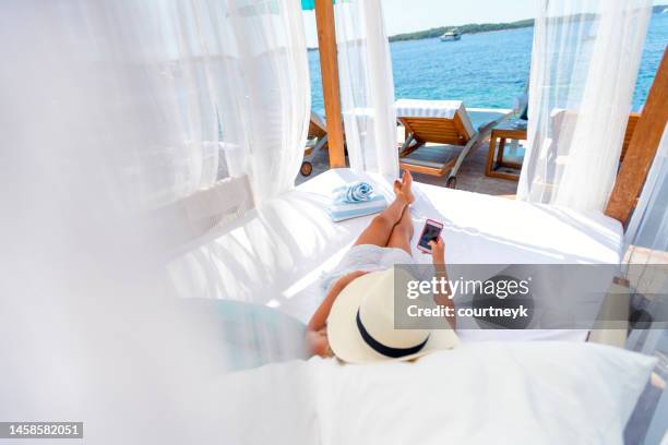 woman resting on a luxurious day bed lounge at an exclusive luxury resort. - kroatien strand stock pictures, royalty-free photos & images