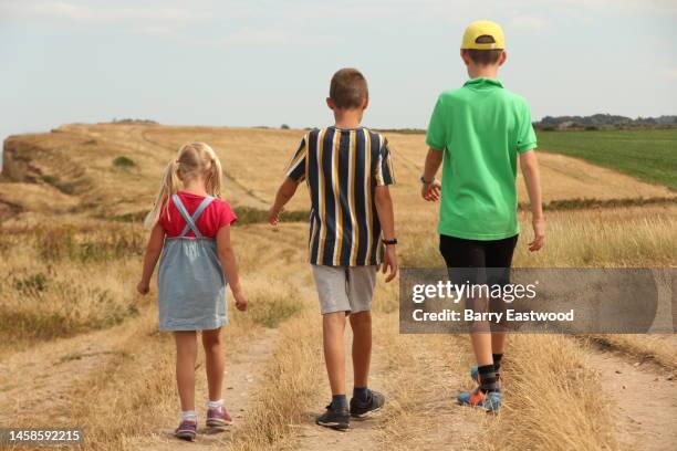 two boys and girl walking along footpath - boy skirt stock pictures, royalty-free photos & images