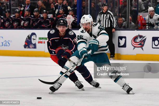 Kent Johnson of the Columbus Blue Jackets attempts to knock the puck away from Erik Karlsson of the San Jose Sharks during the second period of a...