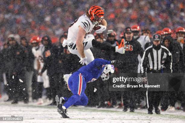 Hayden Hurst of the Cincinnati Bengals jumps over Jaquan Johnson of the Buffalo Bills during the third quarter in the AFC Divisional Playoff game at...