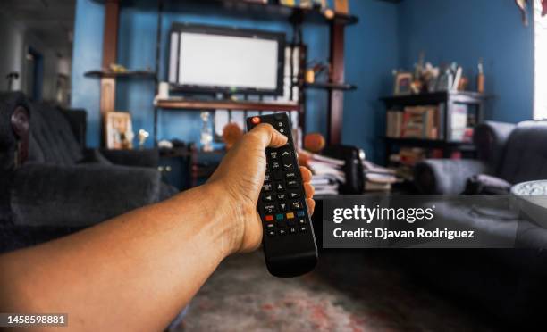 hands holding a remote control watching tv - alter tv stock pictures, royalty-free photos & images