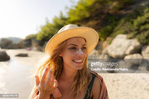 junge frau, die sonnencreme am strand aufträgt - spf 30 stock-fotos und bilder