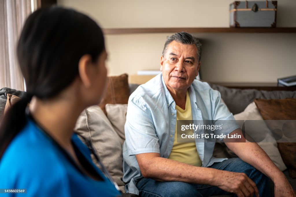 Mature man talking with his nurse during consultation at nursing home