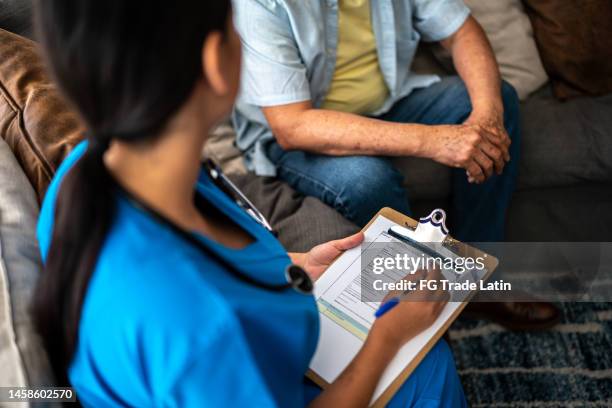 nurse writing on clipboard during consultation at nursing home - questionnaire stock pictures, royalty-free photos & images