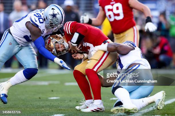 DeMarcus Lawrence and Osa Odighizuwa of the Dallas Cowboys tackle Brock Purdy of the San Francisco 49ers during the first quarter in the NFC...