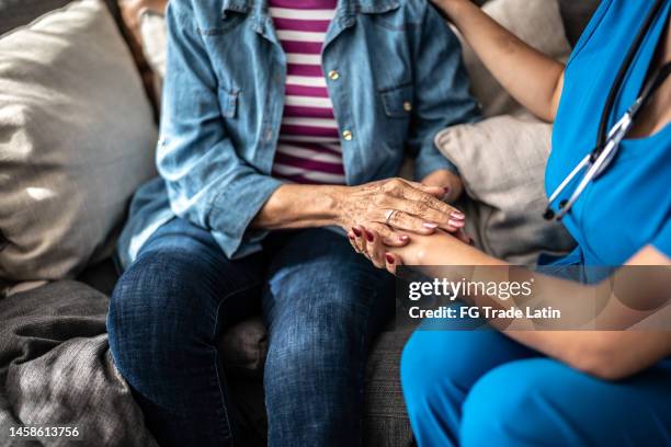 primo piano di una donna anziana e di un'infermiera che si tengono per mano - ospizio foto e immagini stock