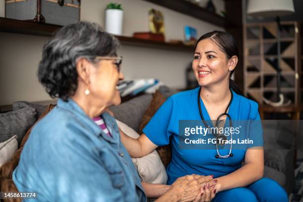 une jeune infirmière discute avec une patiente âgée dans une maison de soins infirmiers - infirmière et maison photos et images de collection