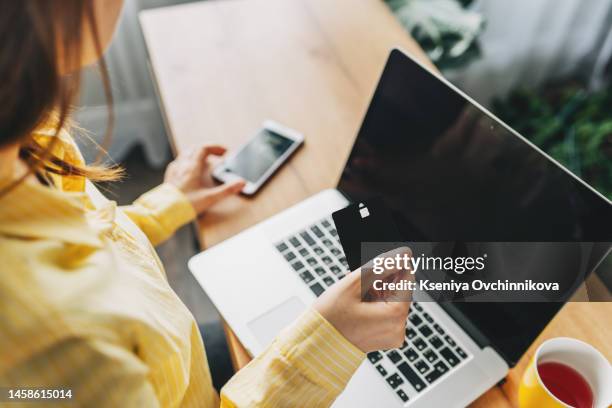 shot of pretty young woman shopping online with credit card and laptop while sitting on the floor at home. - credit score stock pictures, royalty-free photos & images