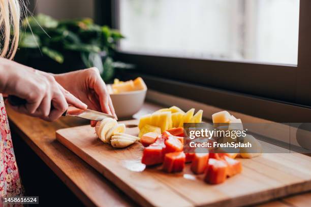 una mujer irreconocible cortando frutas con su nuevo cuchillo - preparación de alimentos fotografías e imágenes de stock