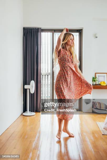 una bella donna bionda felice che si diverte a ballare nel suo appartamento - donne bionde scalze foto e immagini stock
