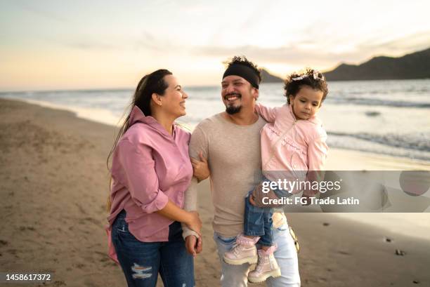 father having fun with her daughter while walking on the beach - family beach vacation stock pictures, royalty-free photos & images