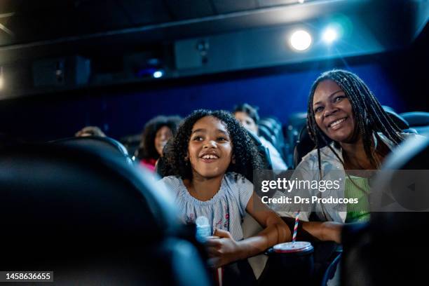 mother and daughter smiling at the cinema - spectator parent stock pictures, royalty-free photos & images