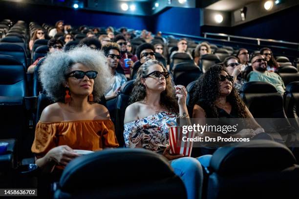 mature female friends watching 3d movie at cinema - venue stock pictures, royalty-free photos & images