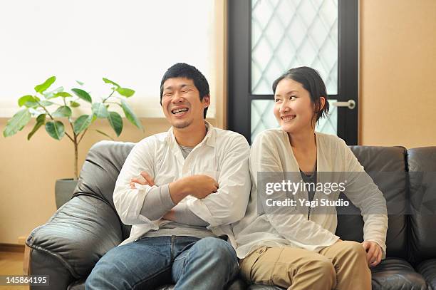 a young married couple sitting on a sofa in a livi - 夫婦 ストックフォトと画像