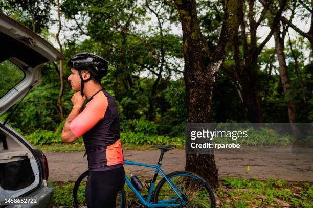 ein radfahrer setzt einen helm auf - radfahren männer stock-fotos und bilder