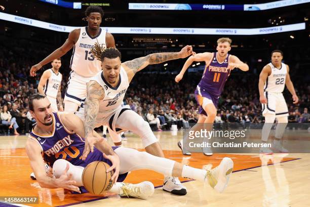 Dario Saric of the Phoenix Suns attempts to control the ball against Brandon Clarke of the Memphis Grizzlies during the first half of the NBA game at...