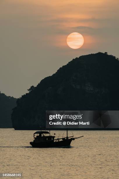 sunset over a boat by the cat ba island in halong bay in vietnam - halong bay stock pictures, royalty-free photos & images