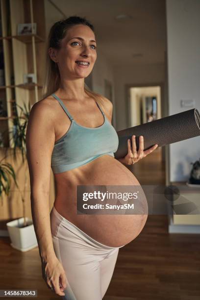 femme enceinte en tenue de sport tenant un tapis de yoga - family yoga photos et images de collection