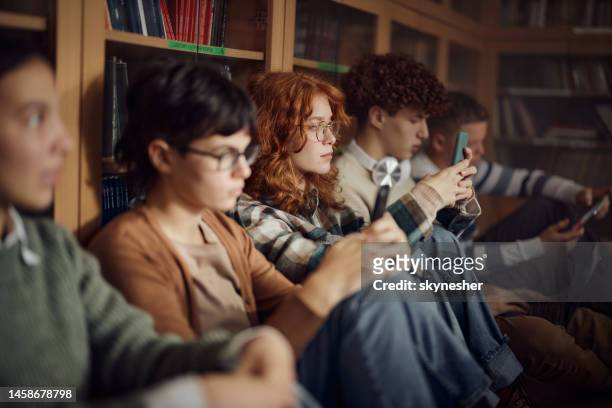 high school students using wireless technology in library. - boys mobile phone group stock pictures, royalty-free photos & images