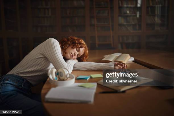 tired redhead student fell asleep in library. - woman sleeping table stock pictures, royalty-free photos & images