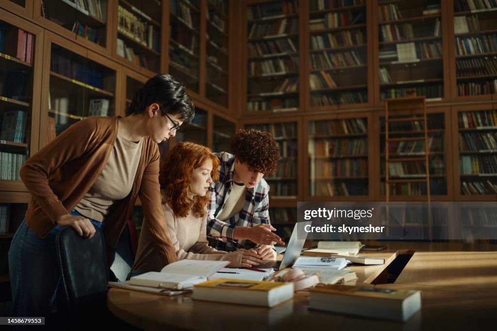 Groupe de lycéens utilisant un ordinateur portable dans la bibliothèque.