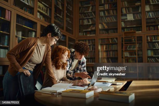 gruppo di studenti delle scuole superiori che utilizzano il computer portatile in biblioteca. - group of university students foto e immagini stock