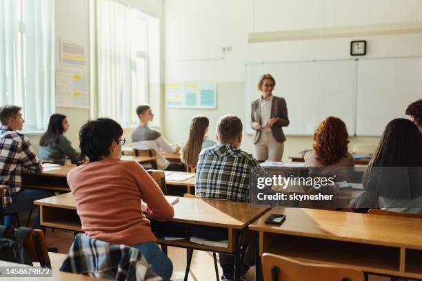 back view of high school students listening to their teach on a class. - students demonstrate in favour of free education stockfoto's en -beelden