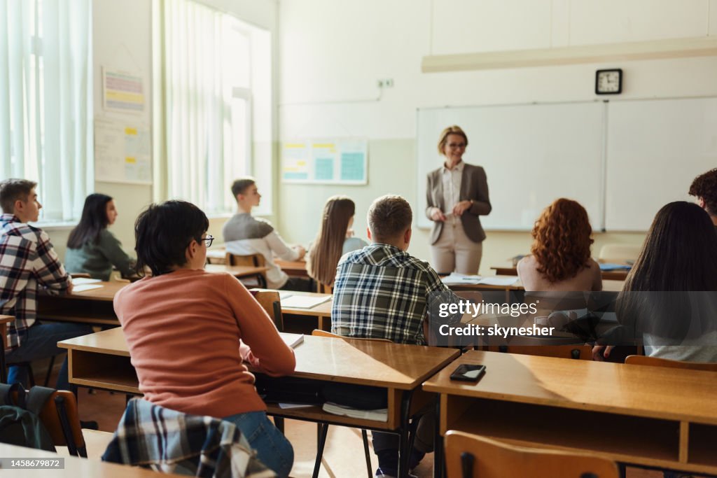 Back view of high school students listening to their teach on a class.