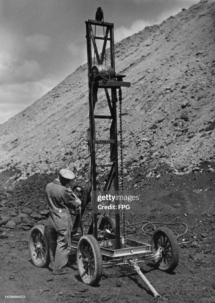 Charge Rig Mine A man using a small drilling rig to place dynamite charges to loosen ...