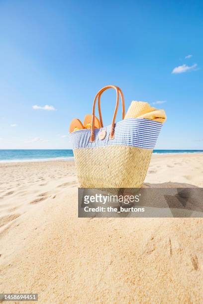 beach bag with blanket and flip-flops at beach and sea against blue sky - beach bag stock pictures, royalty-free photos & images