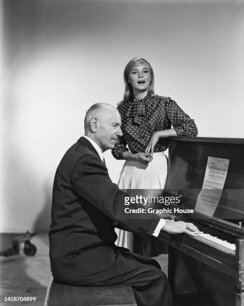 American actress Yvette Mimieux , wearing a polka dot blouse with a white skirt as she sings, accompanied by a man playing the piano, United States,...