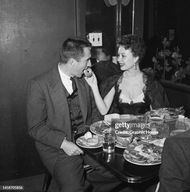 American film producer and talent agent Jack Bean is fed a doughnut by his wife, American actress, singer, dancer and singer Mitzi Gaynor, at Larry...