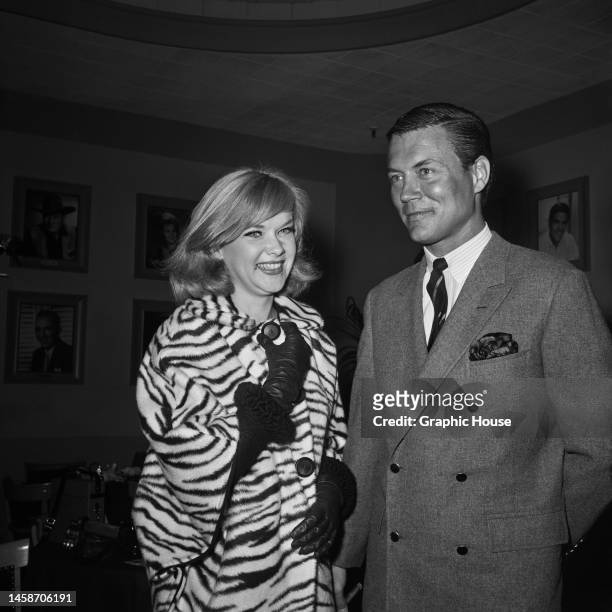 American actress Anne Francis , wearing a zebra-print coat, and American actor and screenwriter Roger Smith , wearing a grey double-breasted jacket,...