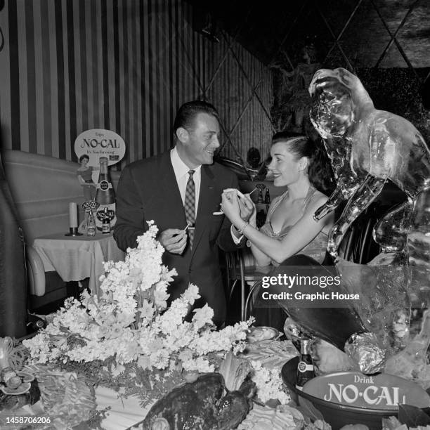American actor Jon Hall and a woman attend a promotional event for No-Cal, with No-Cal products on the table beside them along with an ice sculpture,...