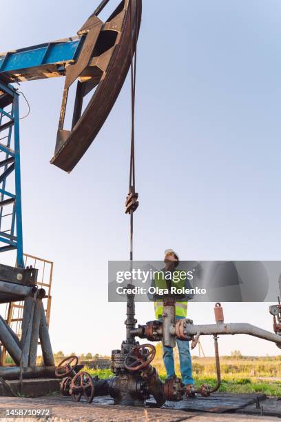 occupation safety. professional male manager with digital tablet checking quality and safety of pipe pressure at oil and gas enterprise - oil well stock pictures, royalty-free photos & images