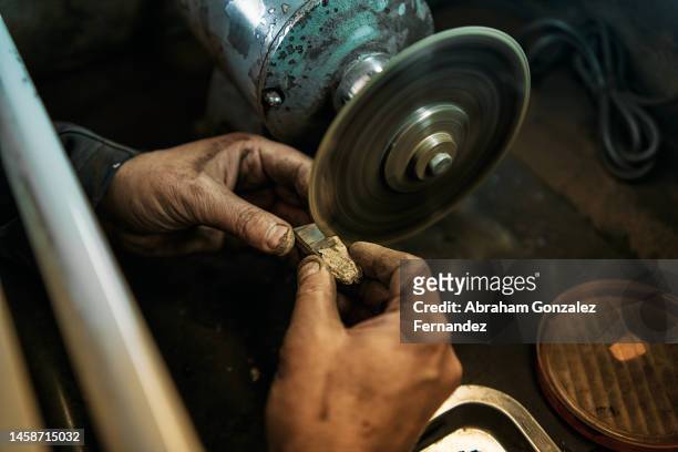 hand of a jeweler holding jet stone while cutting it in his workshop - electric saw stock pictures, royalty-free photos & images