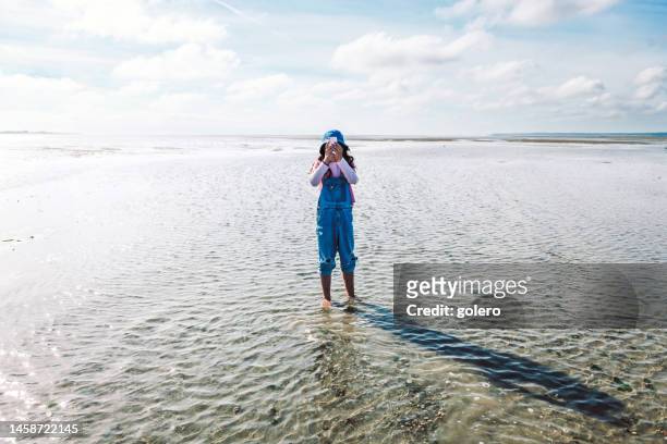 niña tomando una foto móvil y de pie en el agua de mar de marea baja en le crotoy, francia - hauts de france fotografías e imágenes de stock
