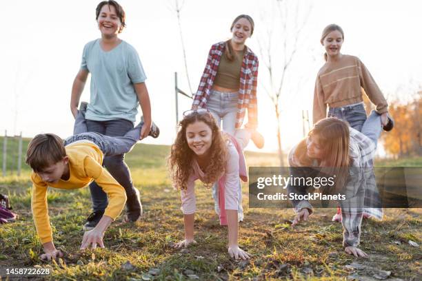 happy children in wheelbarrow race outdoors - vrijetijd sport en spel stockfoto's en -beelden