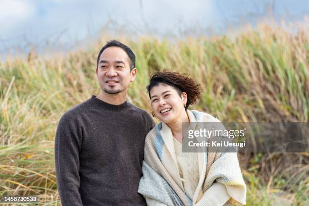 a couple standing by the beach - japanese couple beach stock pictures, royalty-free photos & images