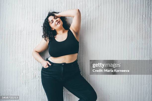 cheerful plus size woman  standing against wall. - curvy model stock-fotos und bilder