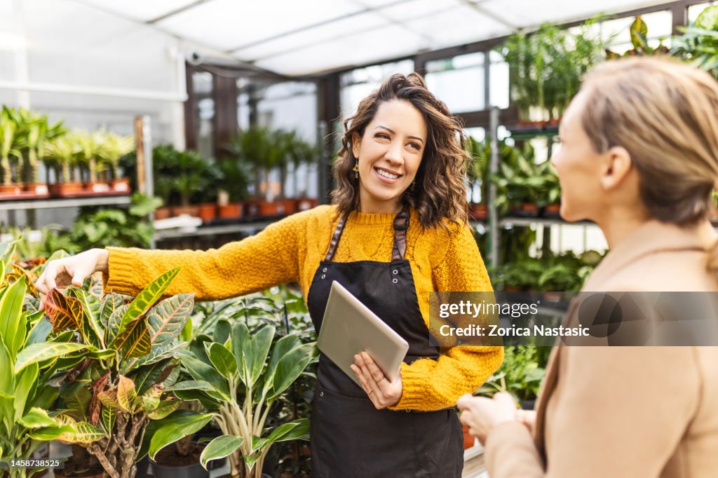 Smiling woman at a garden center talking with an employee