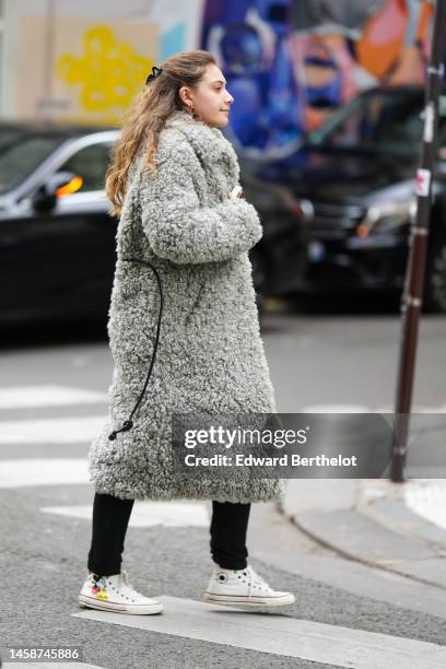 Guest wears a black hair clip, a pale gray oversized fluffy long coat, black denim pants, earrings, white with Mickey Mouse print pattern laces ankle...