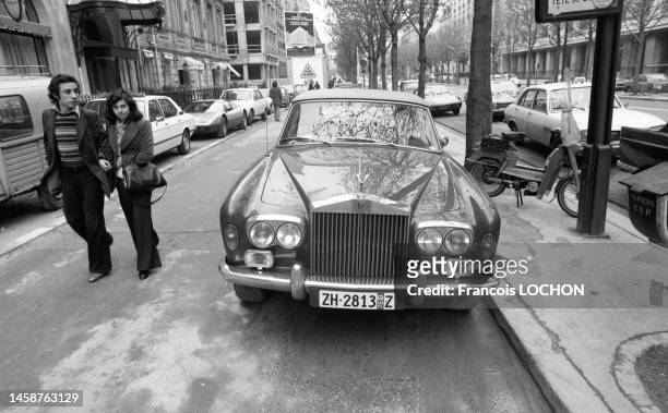 Couple de passants et voiture de luxe Rolls-Royce en avril 1976 à Paris.