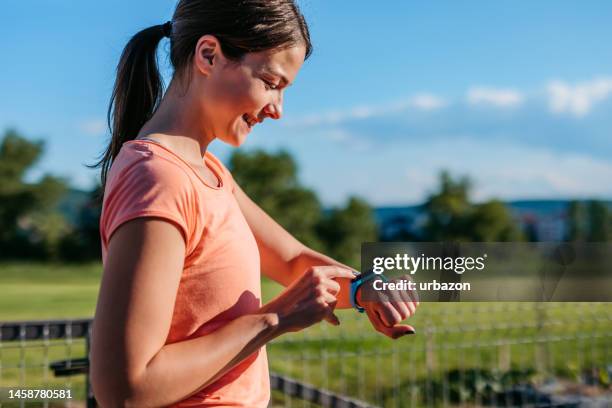 young woman checking pulse on her smartwatch after exercising - fitnesstracker stock pictures, royalty-free photos & images