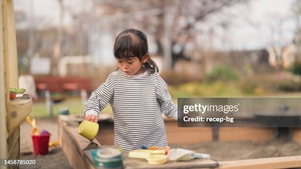 small child playing with sand in public park - 2 girls 1 sandbox stock pictures, royalty-free photos & images