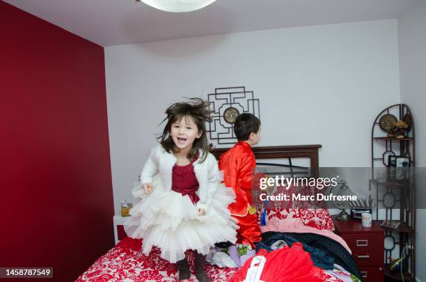 two multiracial kids (chinese and caucasian) jumping on parent's bed - métis stock pictures, royalty-free photos & images