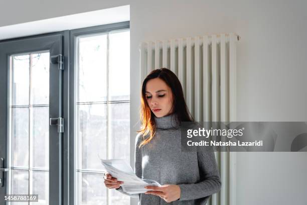 a woman looks worried while checking the electricity bill at home - crisis response stock pictures, royalty-free photos & images
